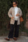 woman wearing a beige knitted maternity cardigan over a white top and black wide-leg pants, holding a brown bag and showing her baby bump