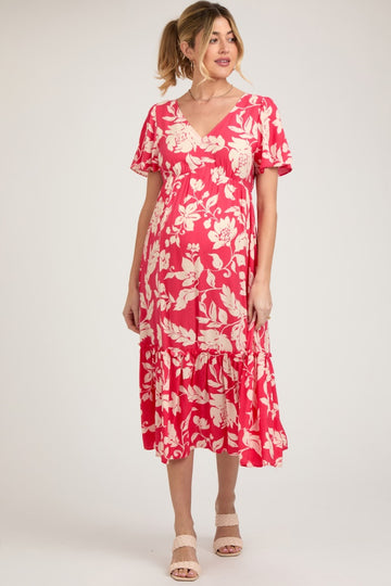 woman wearing a pink floral maternity dress with short sleeves and a tiered skirt, showcasing her baby bump