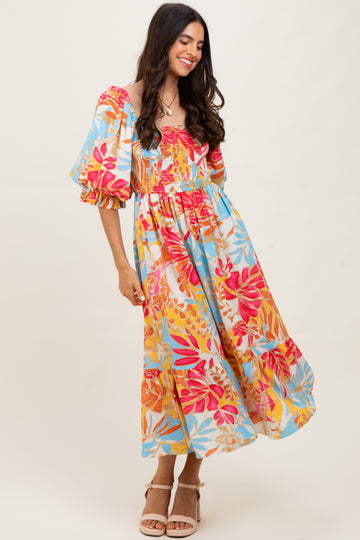 woman wearing a colorful floral maxi dress with puff sleeves and a smocked bodice