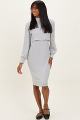 woman wearing a gray two-piece dress with long sleeves and a fitted skirt, posing and smiling