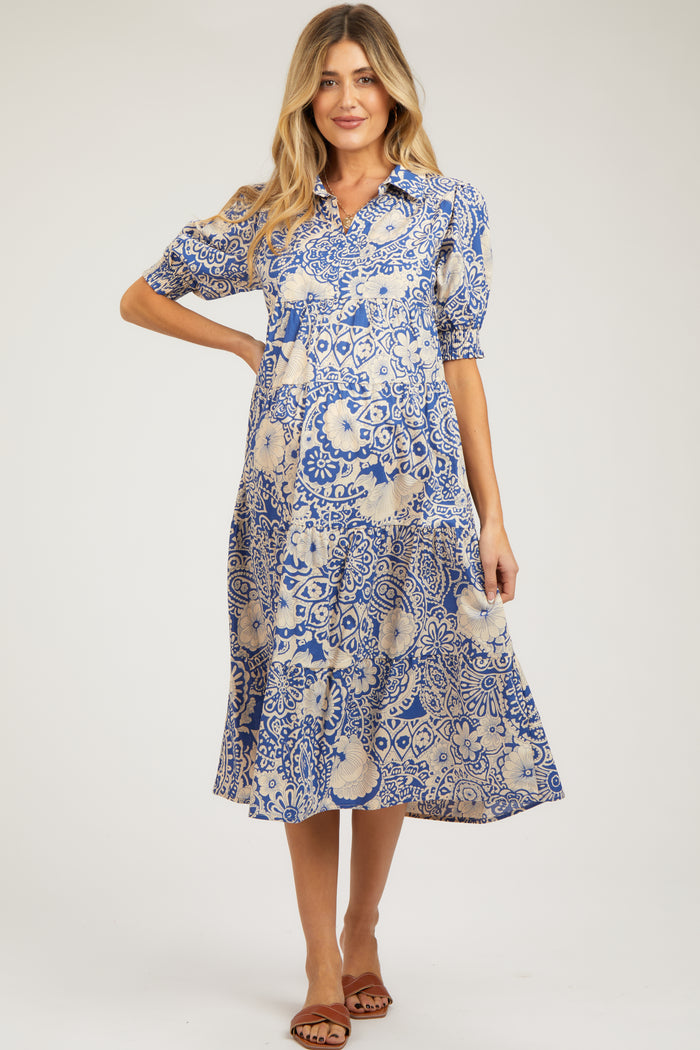 woman wearing a blue and cream patterned maternity dress with short puff sleeves and a flowy skirt, showcasing her baby bump