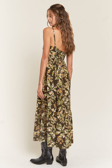 woman wearing a dark floral maxi dress with spaghetti straps and a tiered skirt, viewed from the back