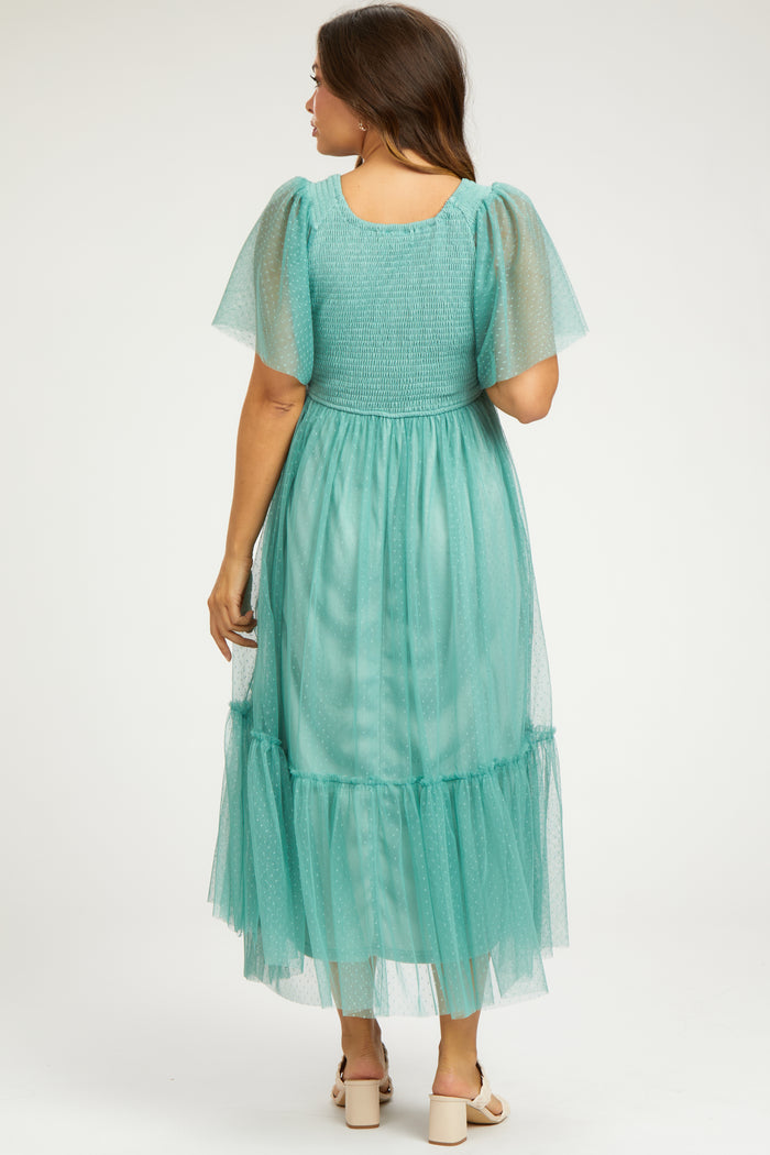 woman wearing a mint green maternity maxi dress with short sheer sleeves and a tiered skirt from the back