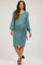 woman wearing a teal maternity dress with long sleeves and a waist tie, showcasing her baby bump