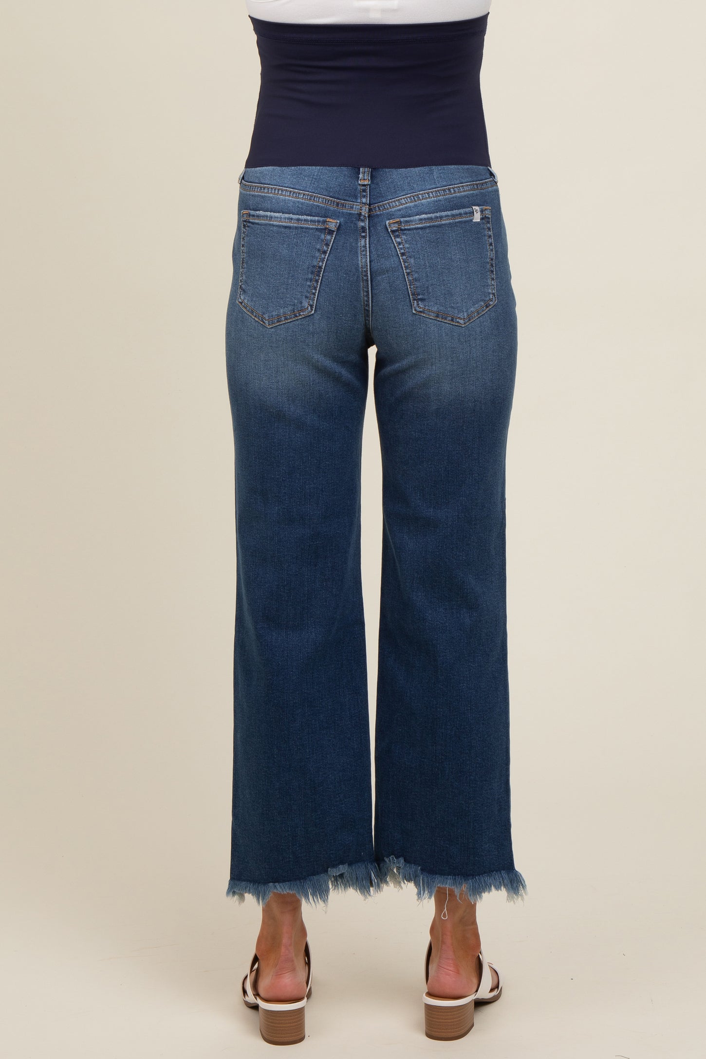 woman wearing dark blue maternity wide-leg jeans with a raw hem, showing the back view and a supportive belly panel