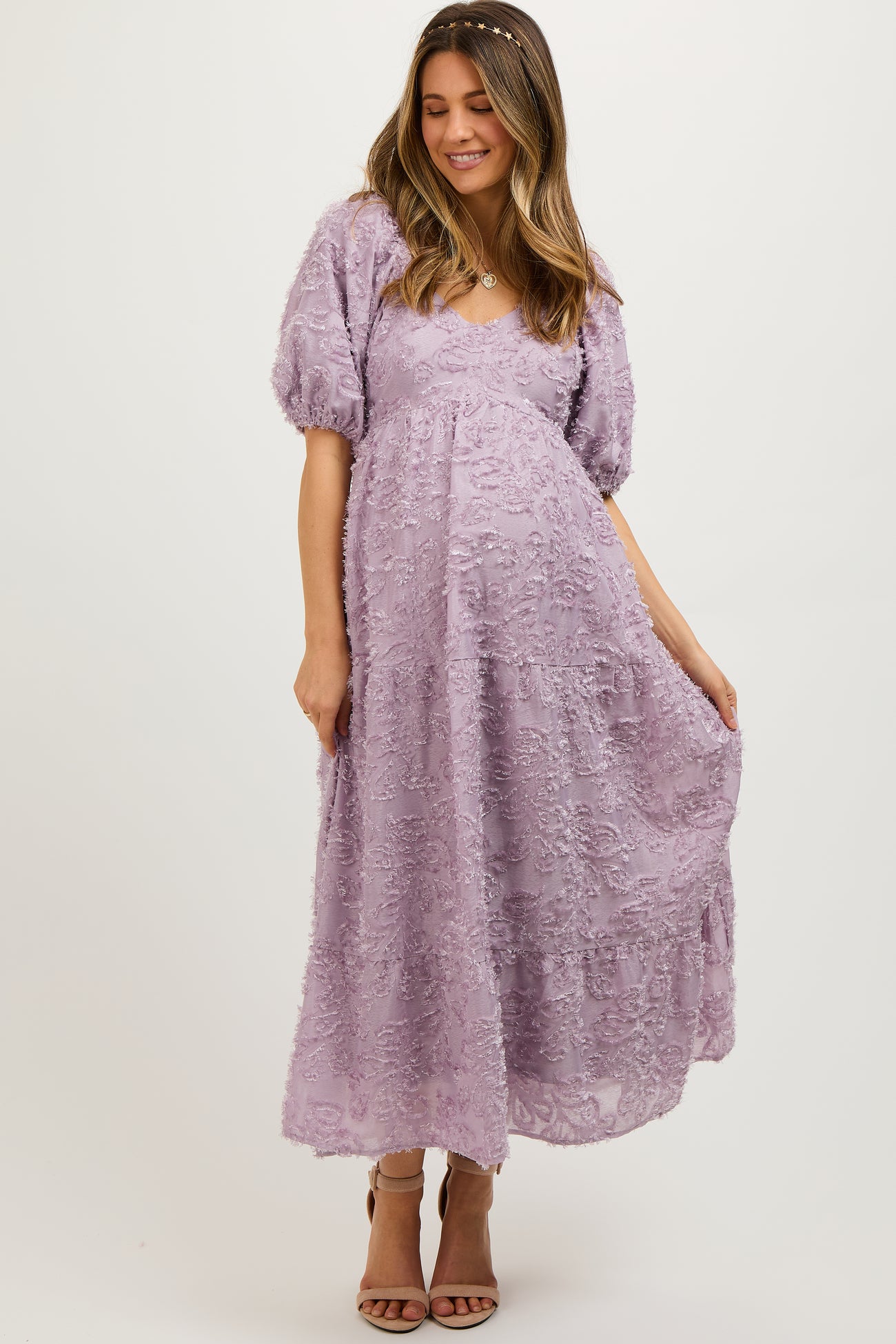 woman wearing a lavender maternity maxi dress with puff sleeves and textured details, displaying her baby bump