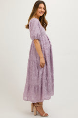 woman wearing a lavender maternity dress with puff sleeves and tiered design, showcasing her baby bump