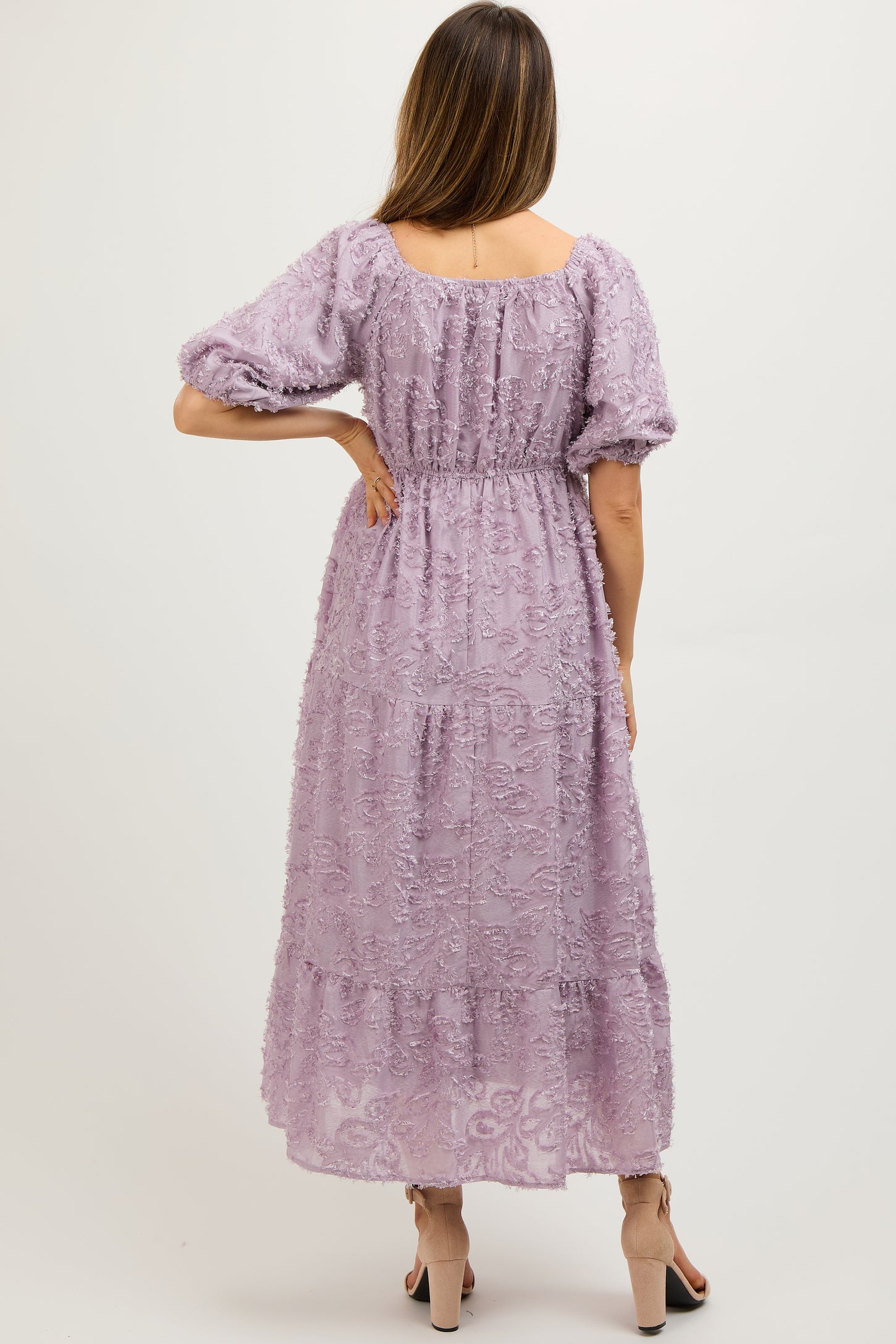 maternity wear in a lilac tiered maxi dress with puff sleeves and textured floral details, model shown from the back