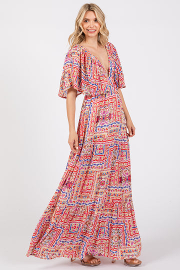 woman wearing a colorful patterned maxi dress with a deep v-neck and flutter sleeves