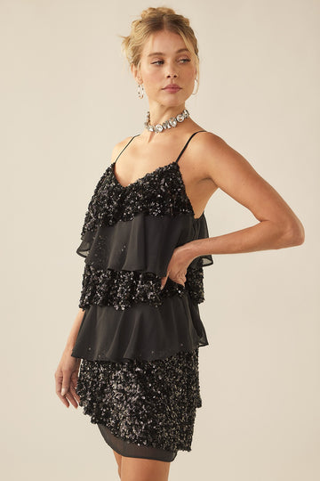 woman wearing a black tiered sequin dress with spaghetti straps and a fitted silhouette