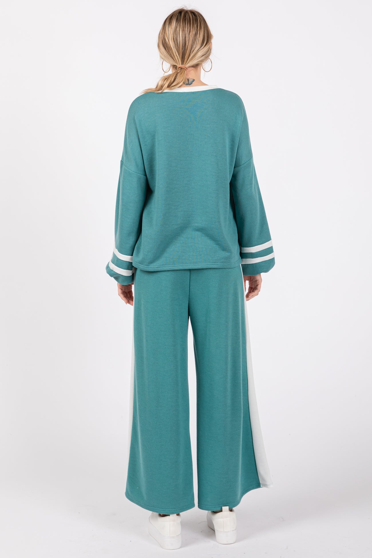 woman wearing a teal two-piece loungewear set with oversized top and wide-leg pants, showing back view