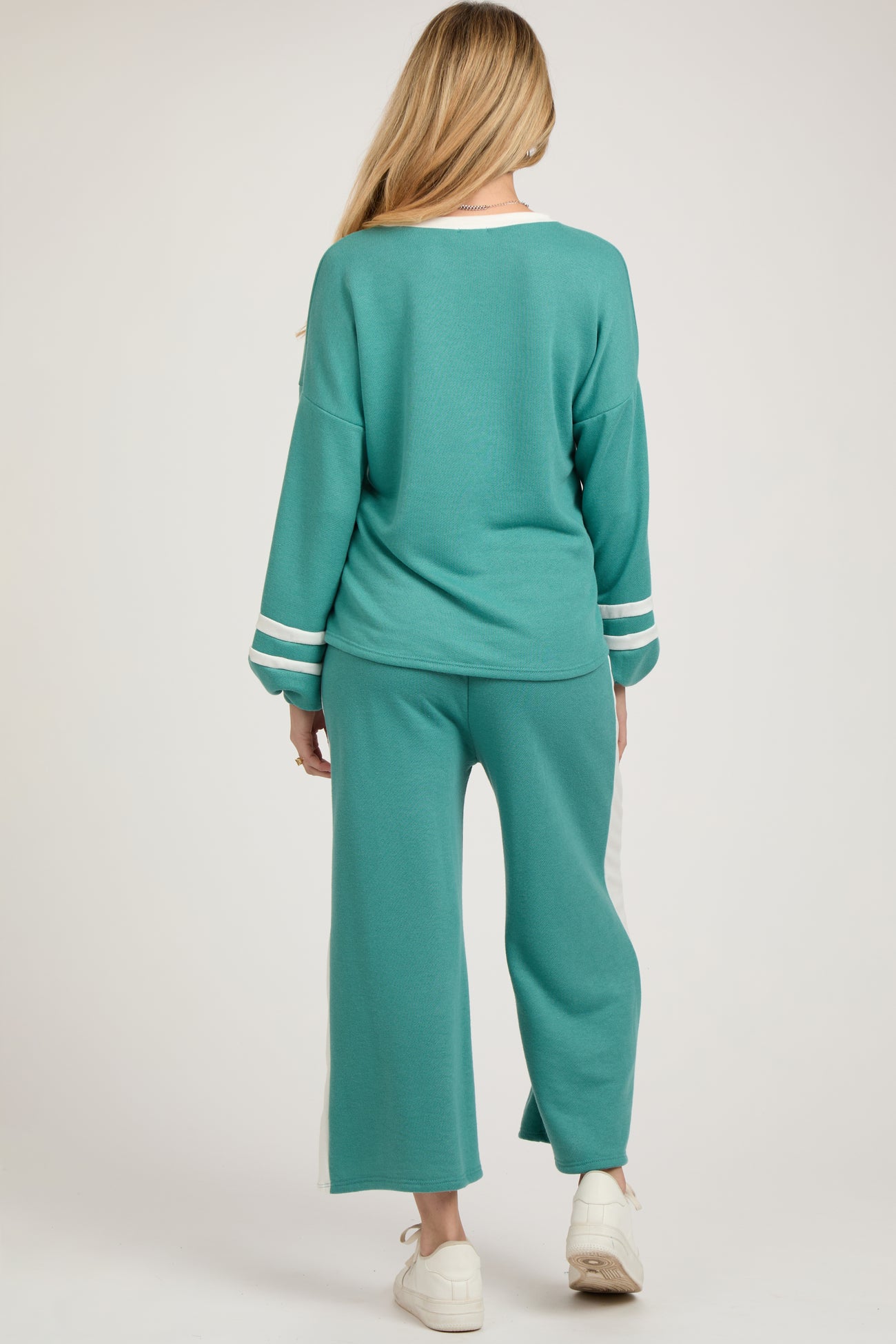 woman wearing a turquoise long sleeve maternity top and matching wide-leg pants with white stripes on the sides