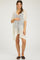woman wearing a white crochet maternity cover-up over a black swimsuit and holding her baby bump