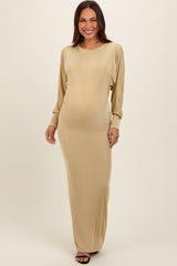woman wearing a gold long sleeve maternity gown with a visible baby bump