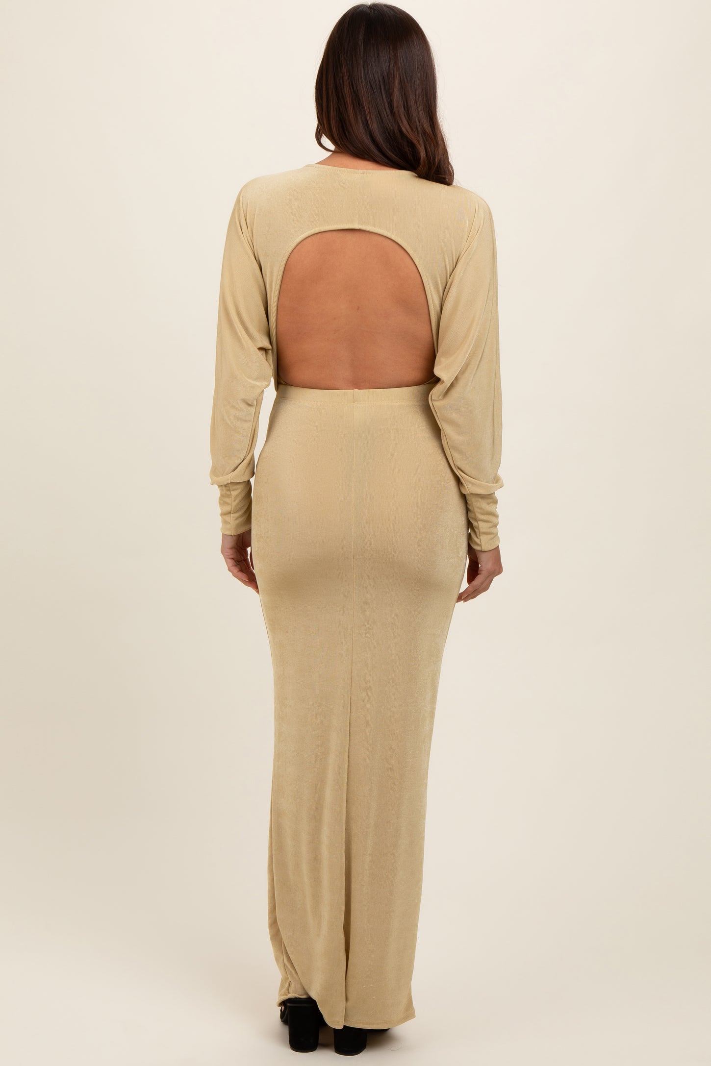 woman wearing a beige long sleeve maternity dress with an open back, showcasing the fit and design
