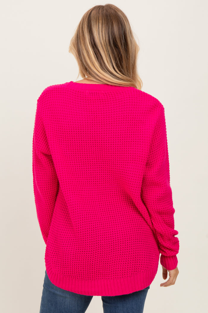 woman wearing a bright pink oversized sweater with a textured knit design and long sleeves, viewed from the back