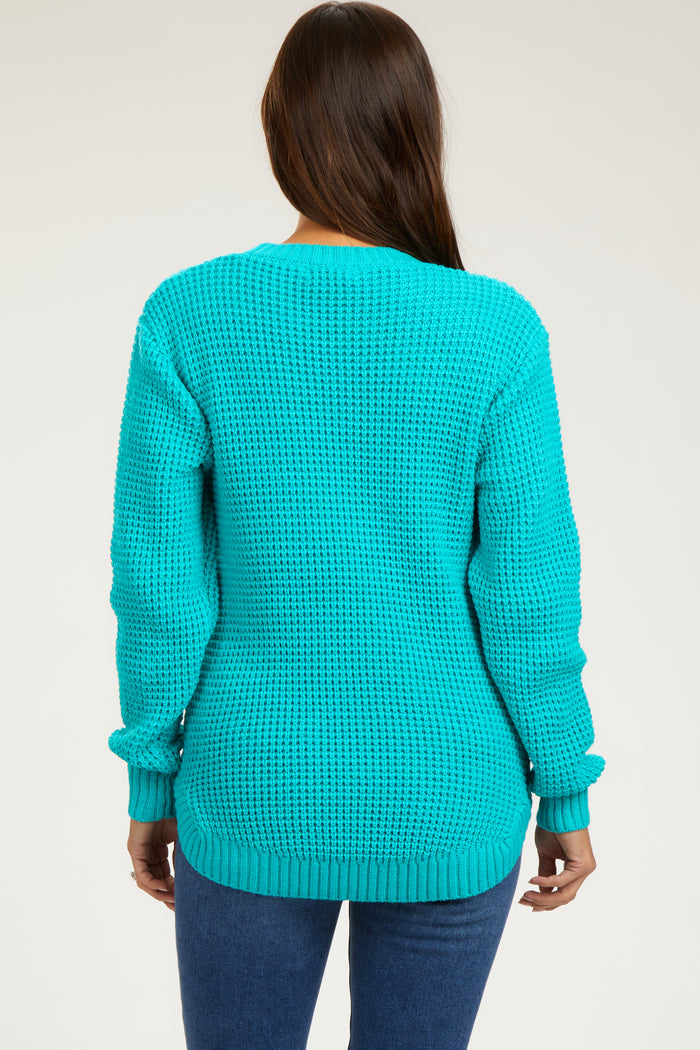 woman wearing a turquoise oversized knitted maternity sweater with long sleeves and back view