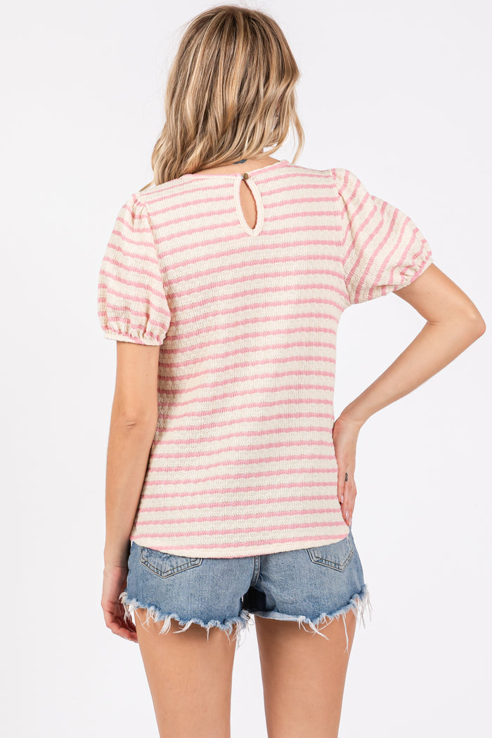 woman wearing a pink and white striped short sleeve top with a back keyhole detail and denim shorts