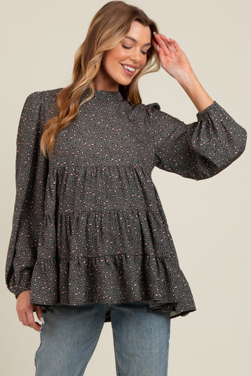 woman wearing a gray maternity top with a tiered ruffle design and long puff sleeves, smiling and posing
