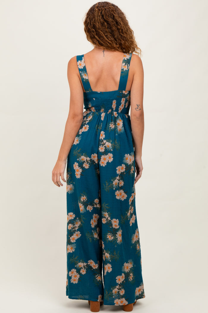 woman wearing a teal floral maxi dress with a smocked back and wide leg pants, standing with her back to the camera