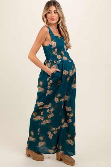 woman wearing a teal floral maternity maxi dress with pockets and a fitted bodice, showcasing her baby bump