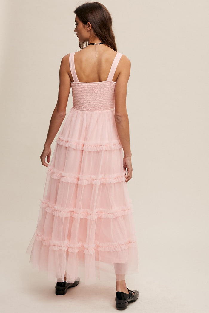 woman wearing a light pink tiered tulle maxi dress with a smocked bodice and wide straps, viewed from the back