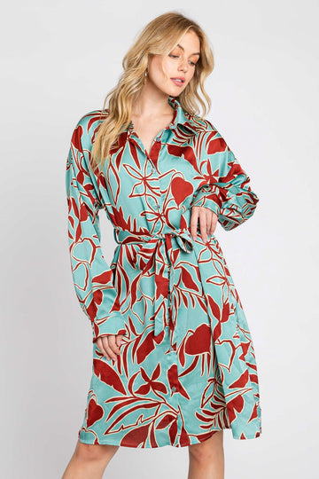 woman wearing a turquoise shirt dress with a red floral print and a belt around the waist