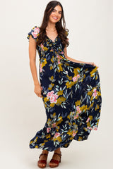 woman wearing a navy floral maxi dress with short sleeves and a ruffled hem, standing and smiling