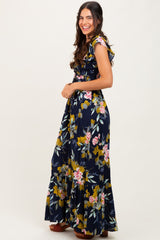 woman wearing a navy floral maxi dress with ruffle sleeves and a tiered hem