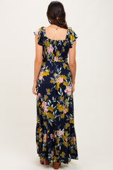 woman wearing a navy blue floral maxi dress with ruffle sleeves and a smocked bodice, viewed from the back