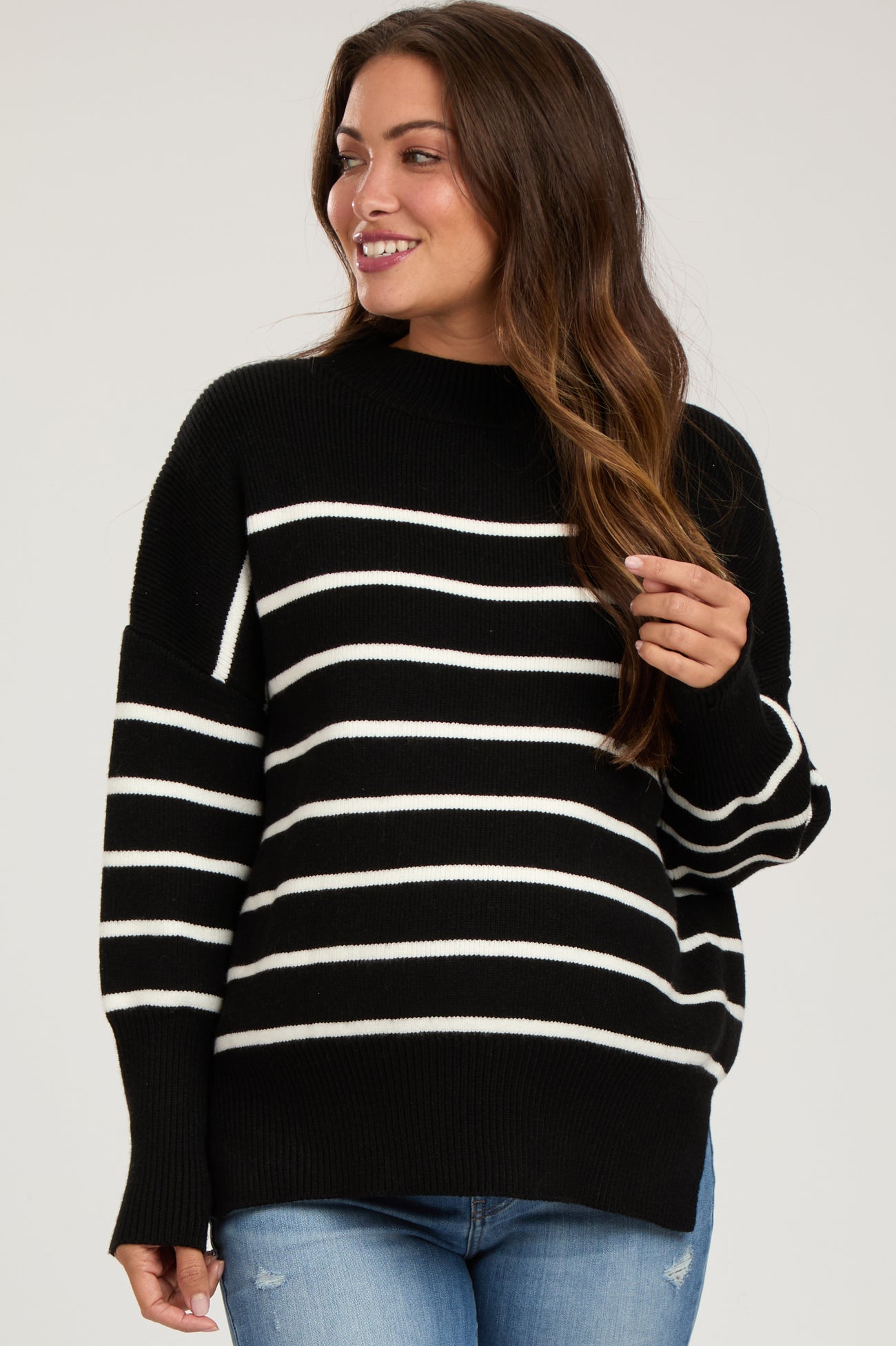 woman wearing a black and white striped maternity sweater with a relaxed fit and crew neckline