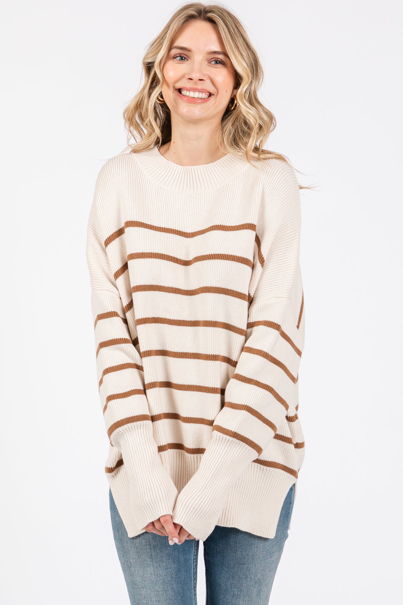 woman wearing a cream and brown striped oversized sweater with long sleeves and relaxed fit