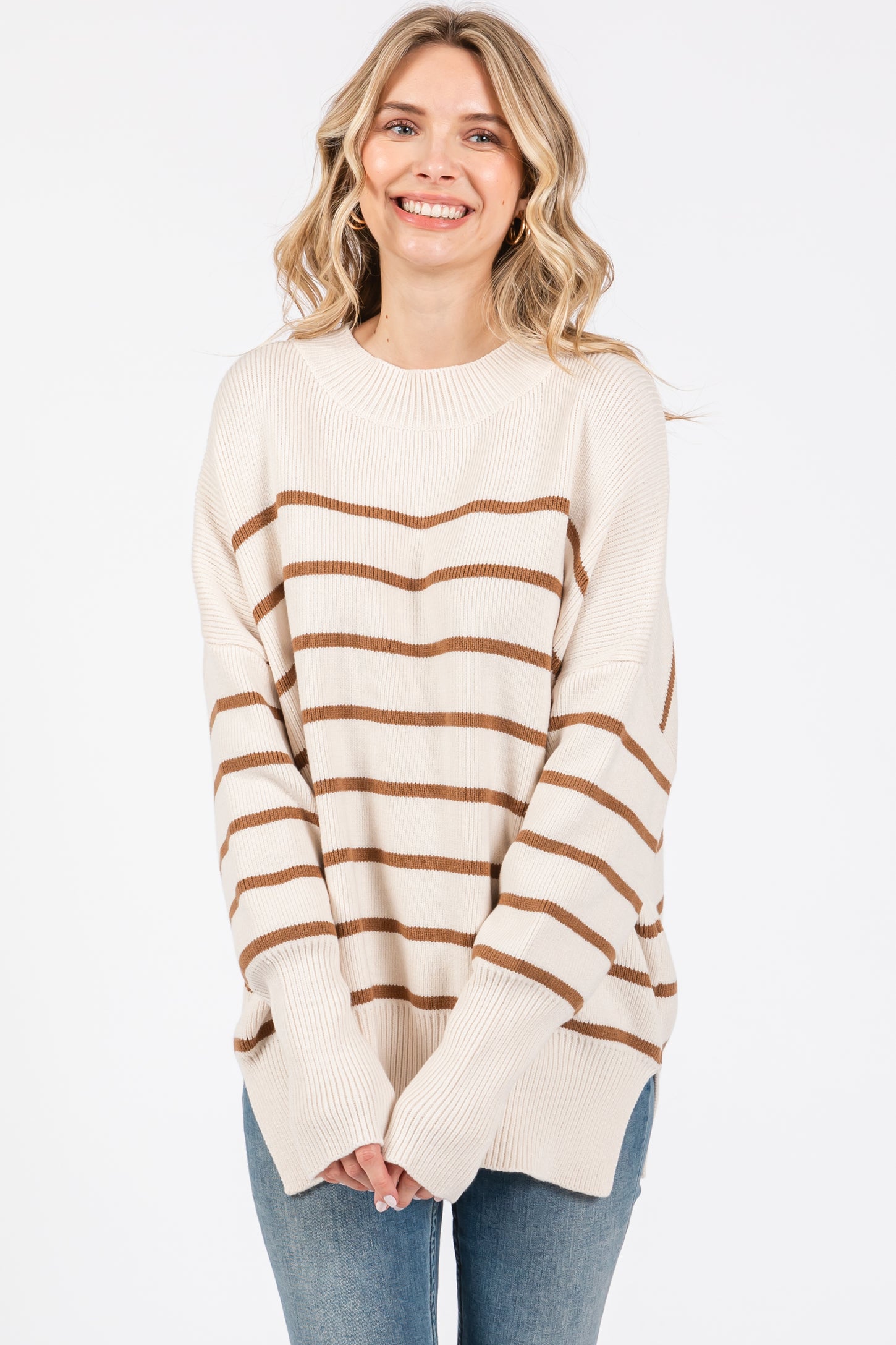 woman wearing a cream and brown striped oversized sweater with long sleeves and relaxed fit
