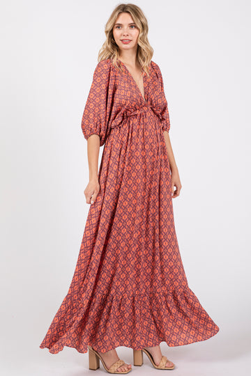 woman wearing a pink patterned maxi dress with a v-neck and puff sleeves, standing in a studio setting