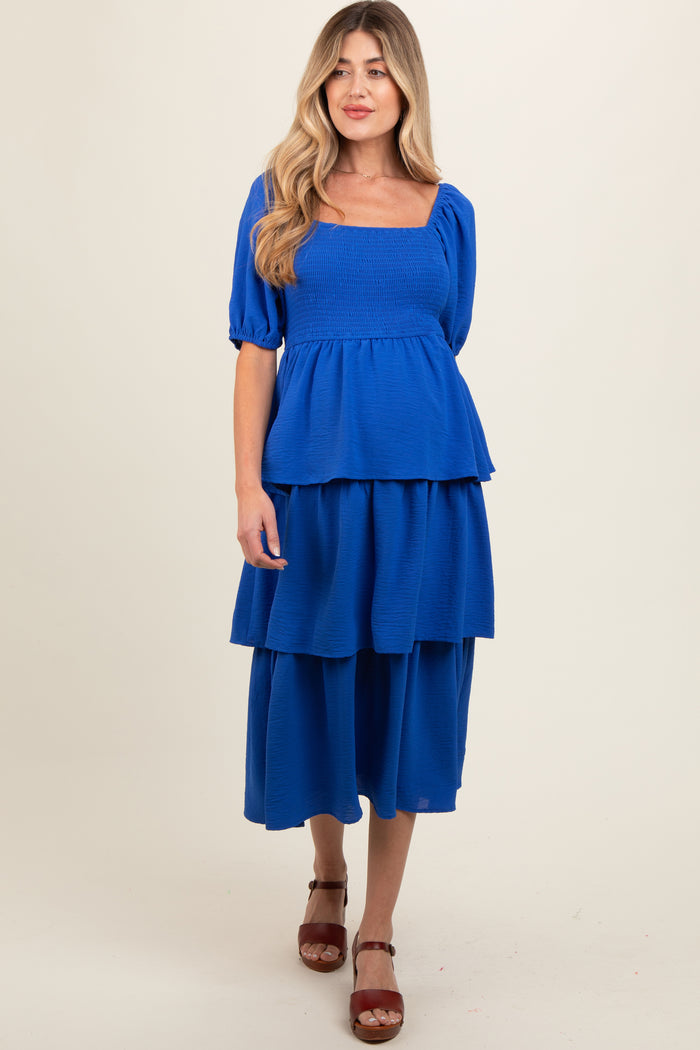 woman wearing a bright blue maternity dress with a square neckline and tiered skirt