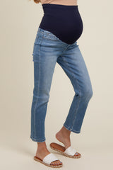 woman wearing a navy blue maternity belly band with light blue cropped maternity jeans and white slip-on sandals, showing baby bump