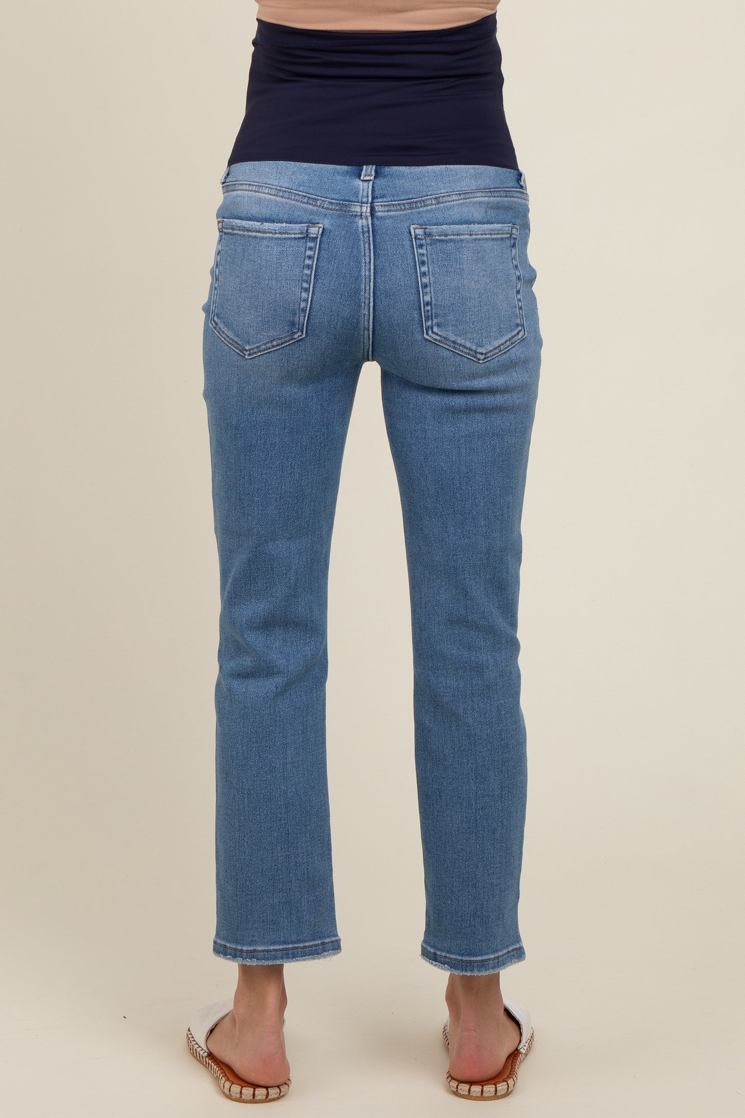 woman wearing a pair of blue maternity jeans, showing the back view with a fitted waist and straight leg cut
