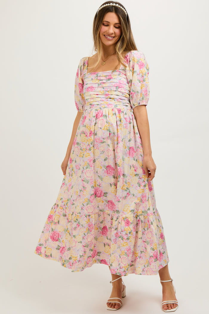 woman wearing a floral maternity dress with puff sleeves and a tiered skirt, showcasing a baby bump