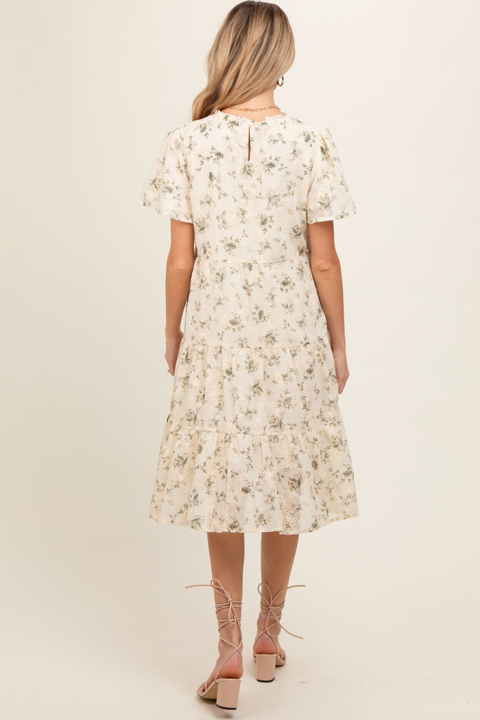 woman wearing a floral maternity dress with short sleeves and a tiered skirt, showing a baby bump from the back