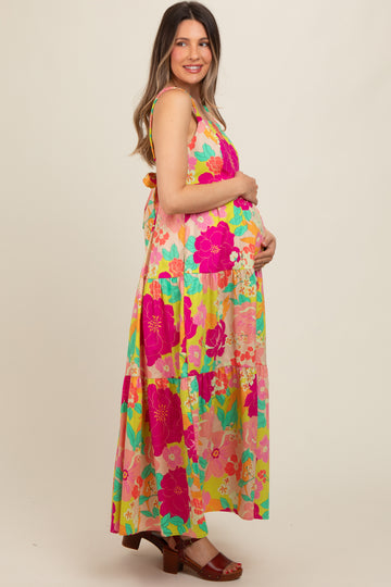 woman wearing a colorful floral maternity maxi dress and holding her baby bump