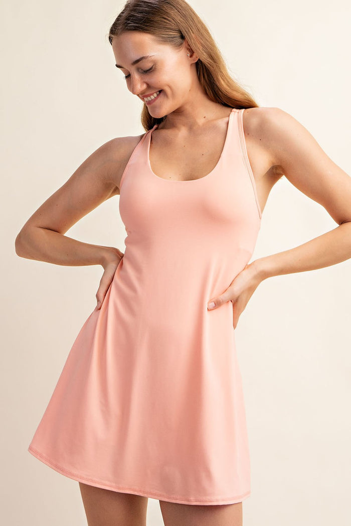 woman wearing a pink athletic tank dress with a fitted bodice and flared skirt