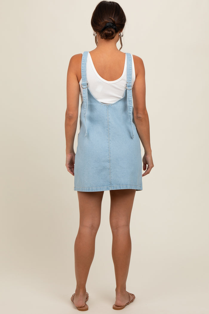 woman wearing a light blue denim maternity dress with adjustable straps, viewed from the back