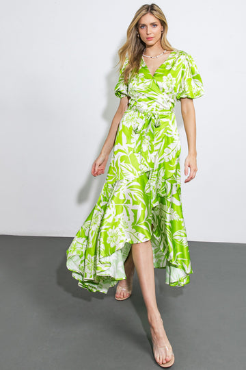 woman wearing a vibrant green floral wrap dress with short puff sleeves and a high-low hemline