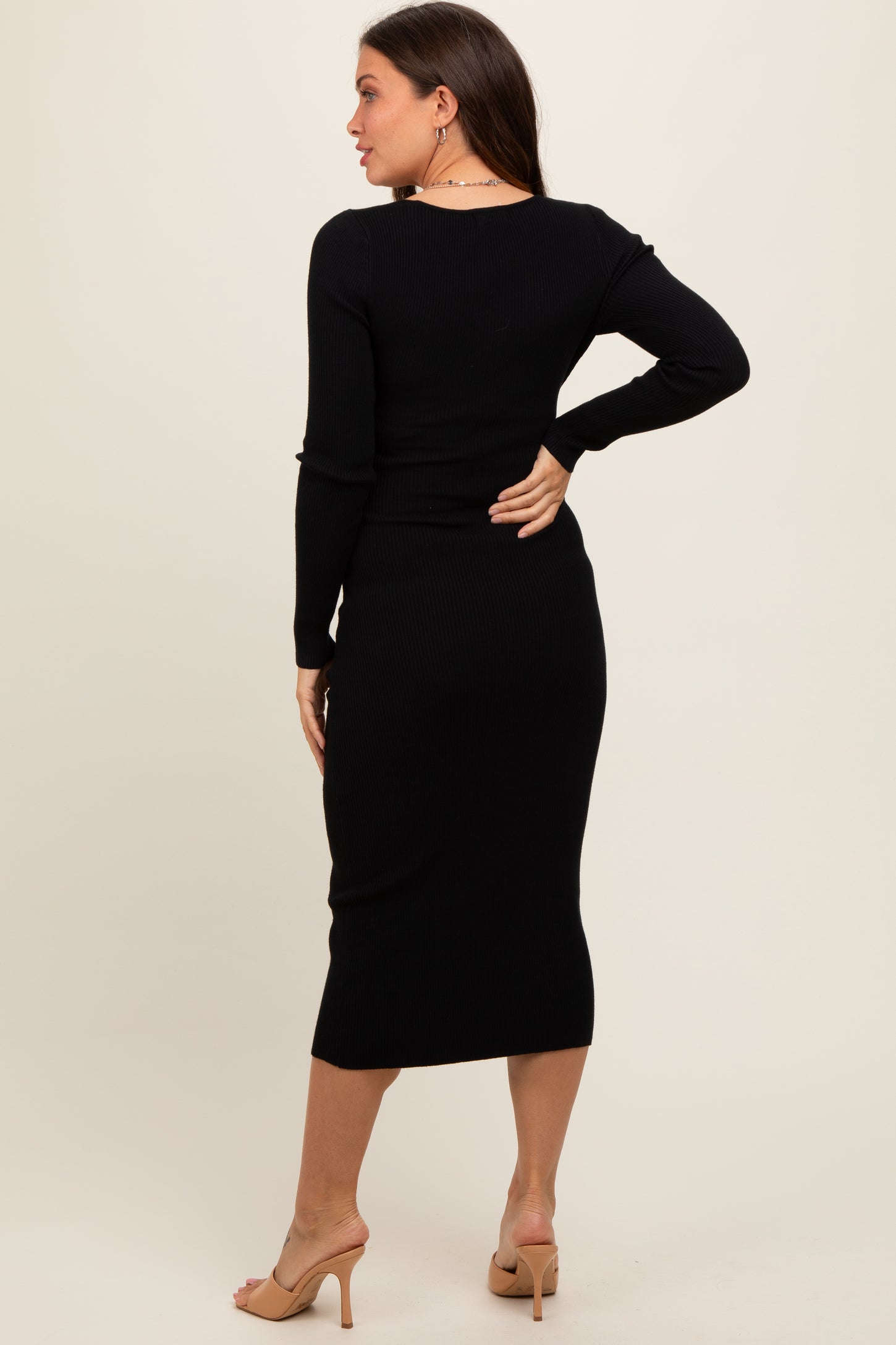 maternity wear in black ribbed long sleeve dress, showing a fitted silhouette and knee-length style from the back