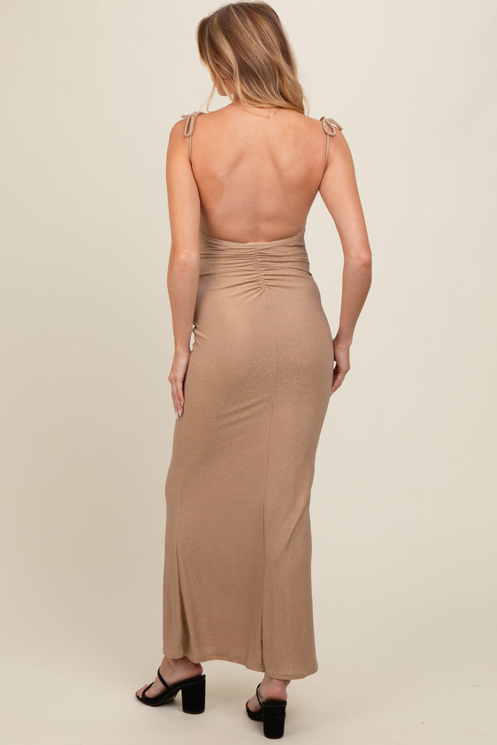 woman wearing a backless tan maternity maxi dress with tie straps and ruching detail