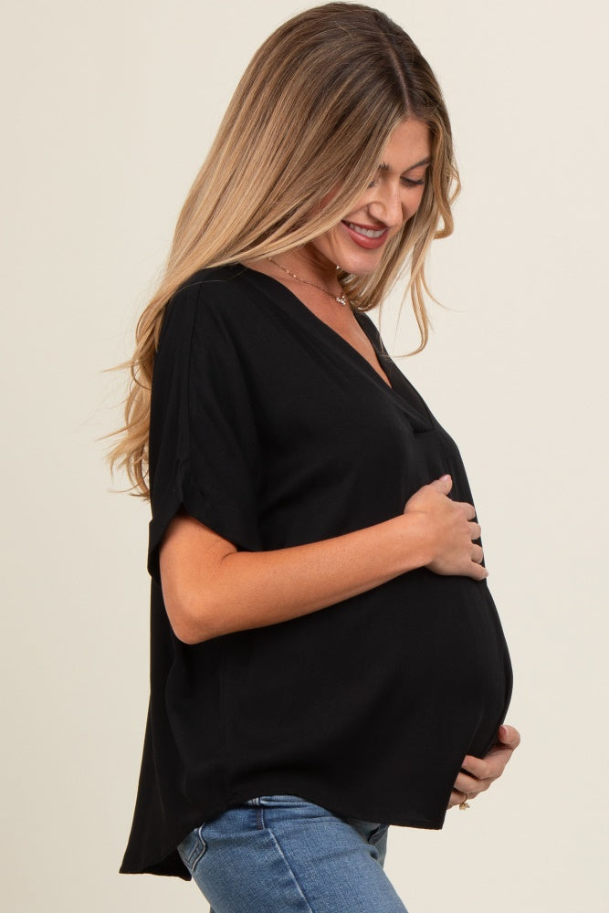 woman wearing a black maternity top and holding her baby bump