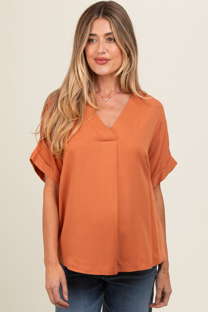 woman wearing an orange v-neck maternity top with short sleeves and a relaxed fit