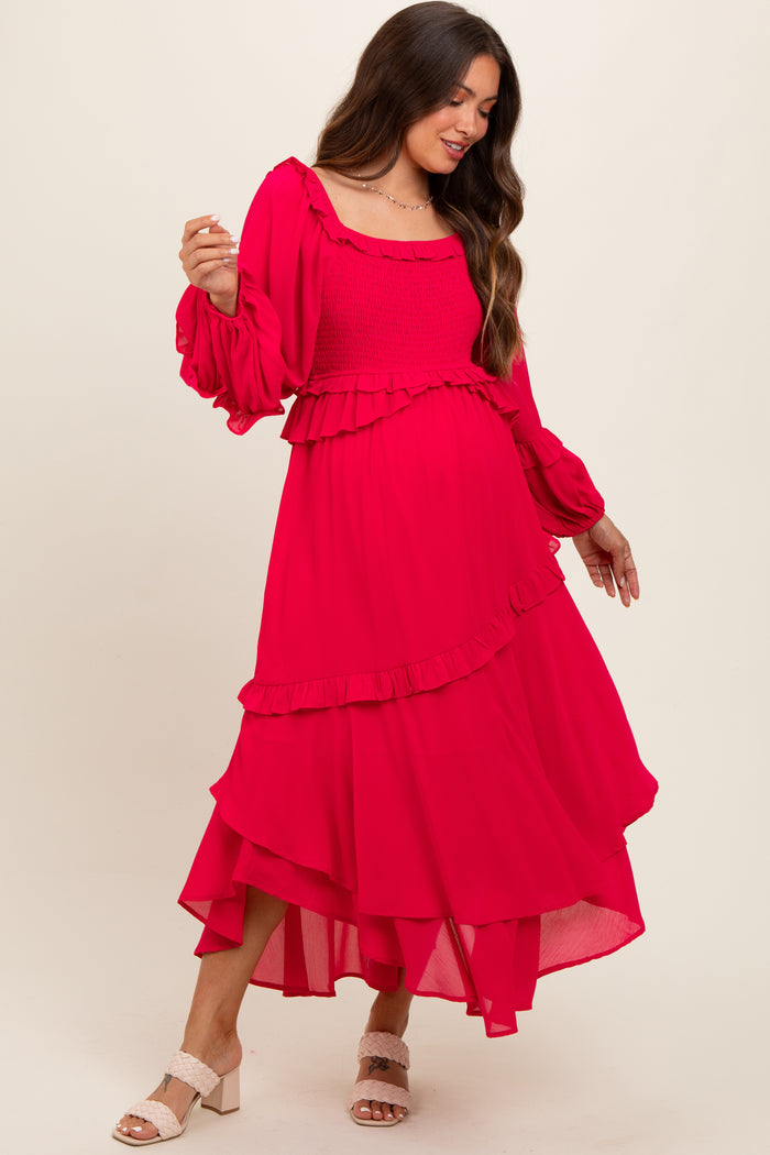 woman wearing a bright pink maternity dress with ruffle details and long sleeves, showcasing her baby bump