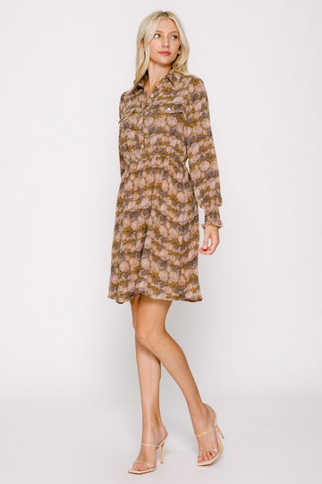 woman wearing a patterned brown and pink long sleeve shirt dress with a cinched waist and a flared skirt