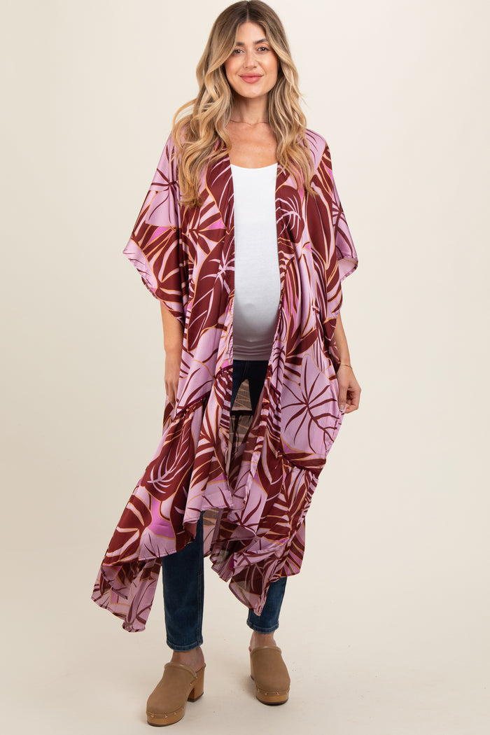 woman wearing a floral maternity kimono in shades of pink and burgundy with an open front and relaxed fit, holding her baby bump